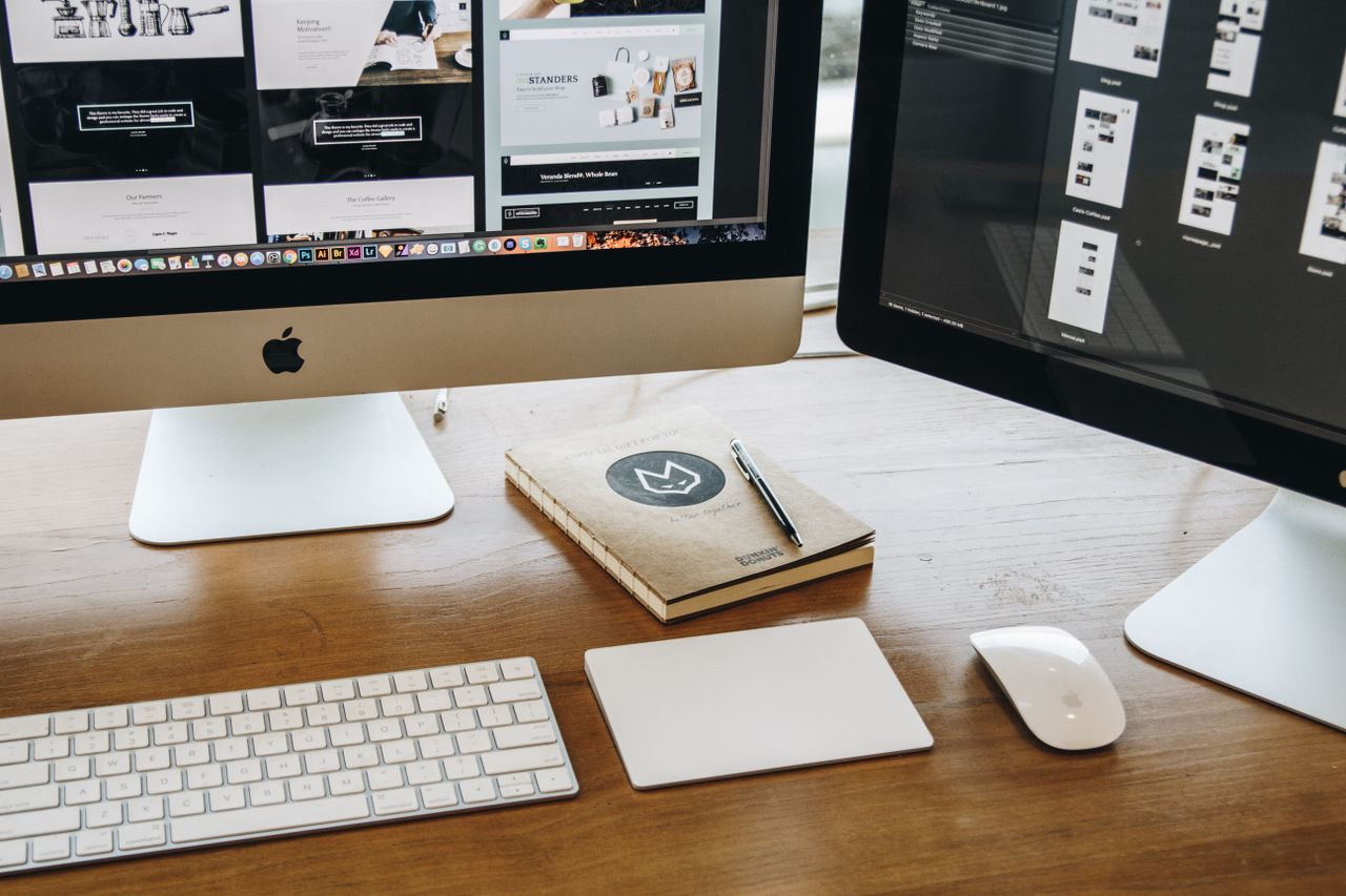 Un bureau minimaliste avec deux écrans, un clavier, une souris et un carnet, pensé pour la productivité.